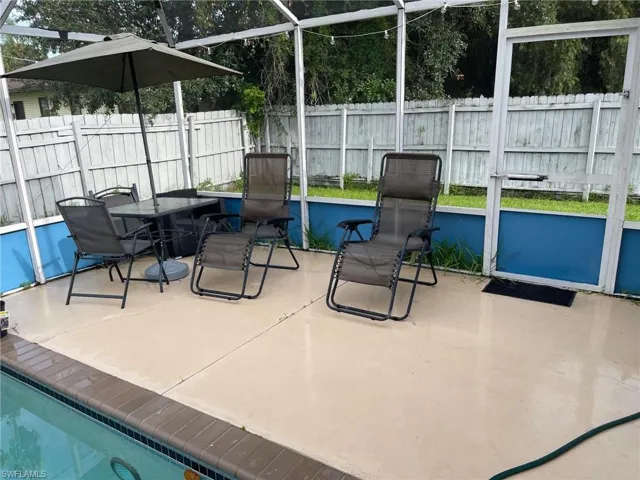 View of patio / terrace with a fenced backyard, outdoor dining space, and glass enclosure