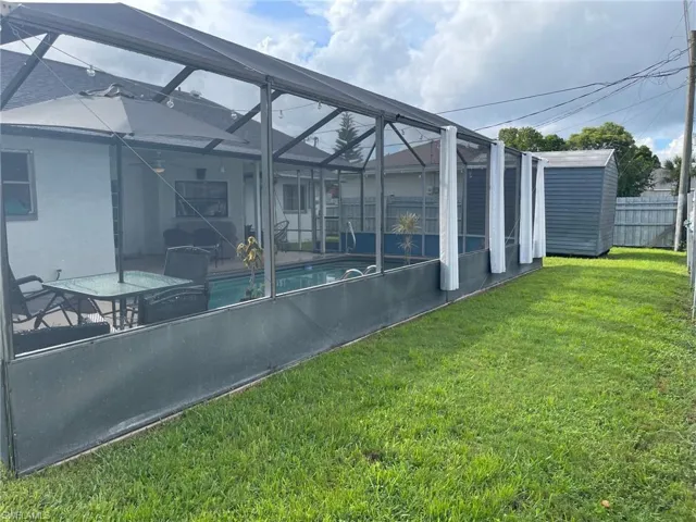 View of yard with a storage shed, an outdoor structure, and a lanai
