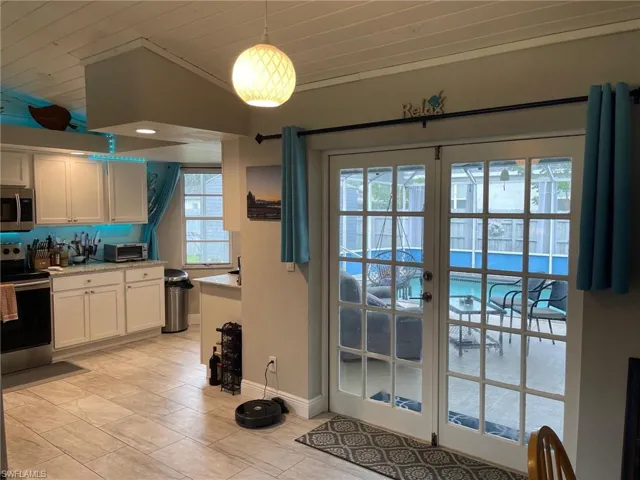 Kitchen featuring stainless steel appliances, white cabinetry, lofted ceiling, wood ceiling, and french doors
