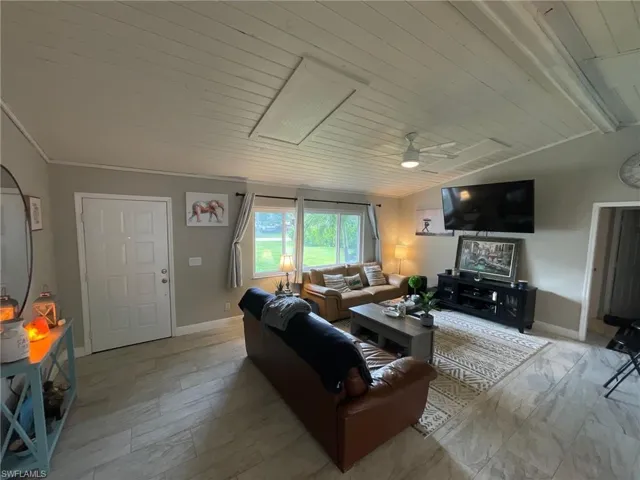 Living room with ceiling fan, baseboards, and wooden ceiling