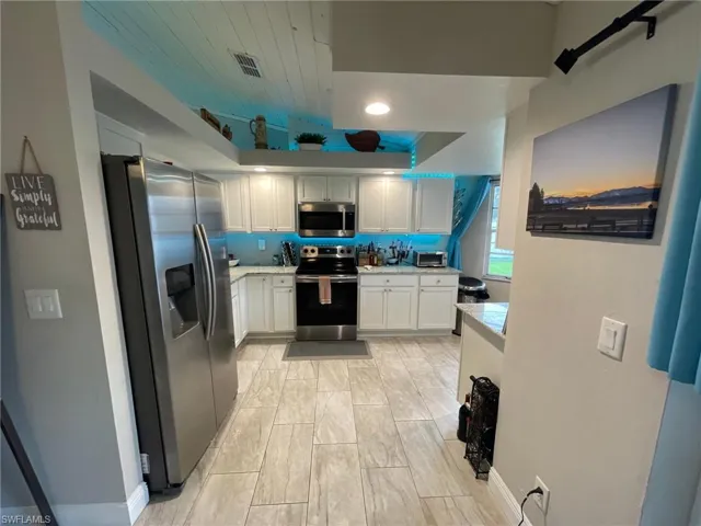 Kitchen with stainless steel appliances, light countertops, and white cabinets