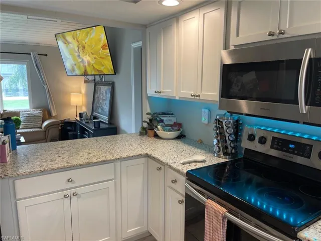 Kitchen featuring appliances with stainless steel finishes, white cabinets, and light stone countertops