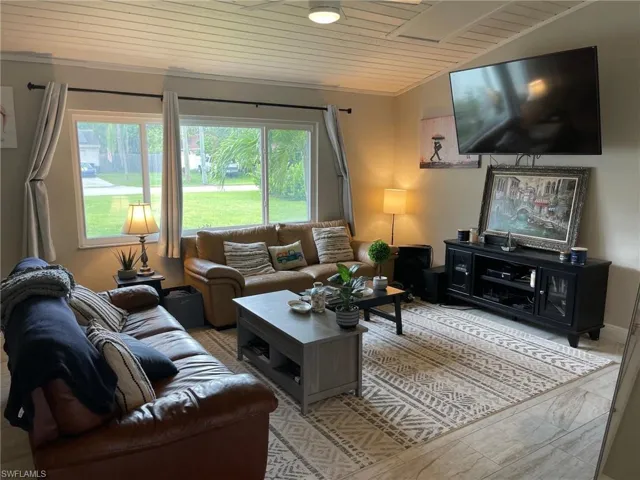Living area featuring wood ceiling, vaulted ceiling, and crown molding