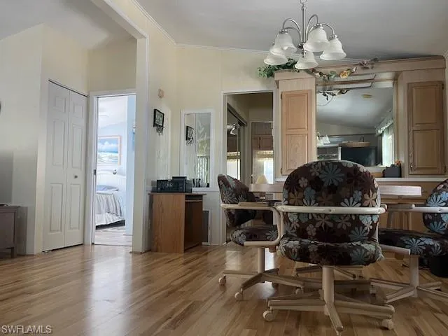Dining room with ornamental molding, an inviting chandelier, and light hardwood / wood-style floors