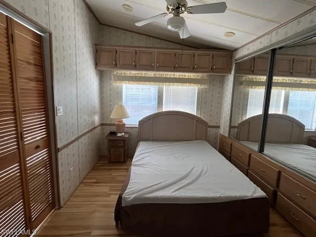 Bedroom with light hardwood / wood-style flooring, multiple windows, vaulted ceiling, and a closet