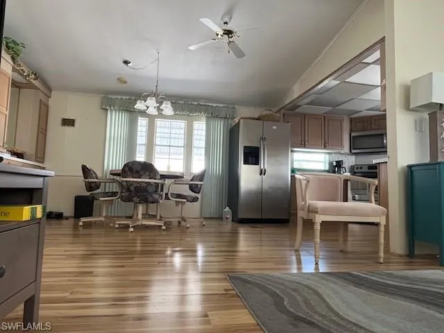 Dining space with ceiling fan with notable chandelier, lofted ceiling, and hardwood / wood-style floors