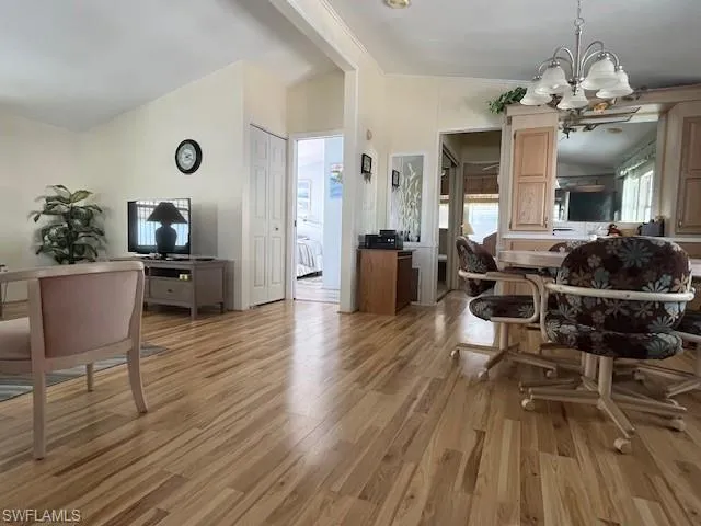 Dining space featuring a notable chandelier, vaulted ceiling, and light wood-type flooring