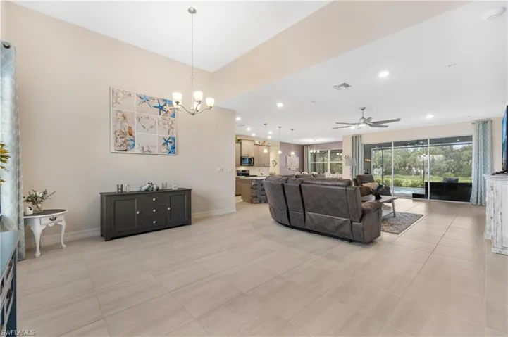 Living room with ceiling fan with notable chandelier and light tile patterned flooring