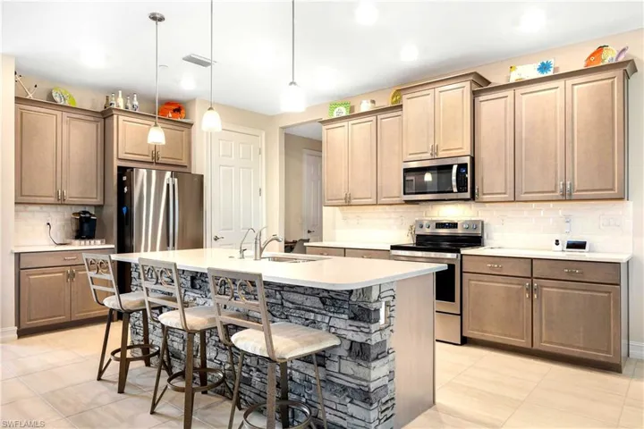 Kitchen featuring backsplash, stainless steel appliances, sink, a breakfast bar, and a center island with sink