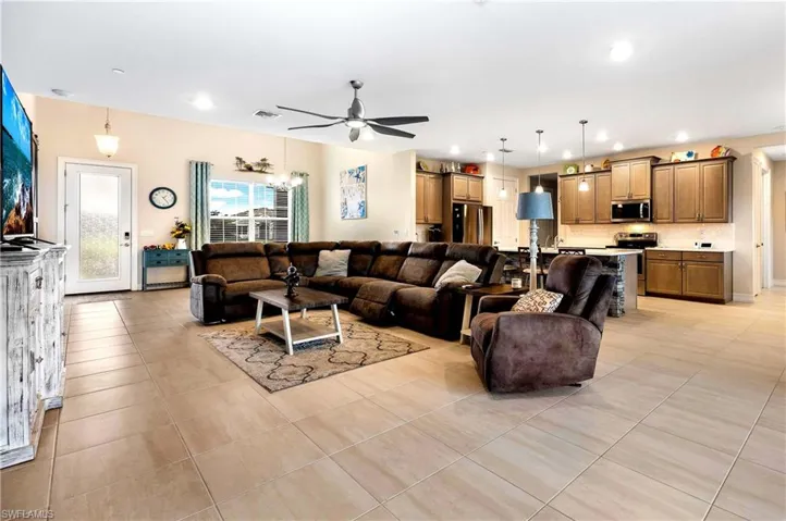 Tiled living room with ceiling fan with notable chandelier