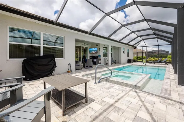 View of swimming pool with a lanai, a patio, and an in ground hot tub