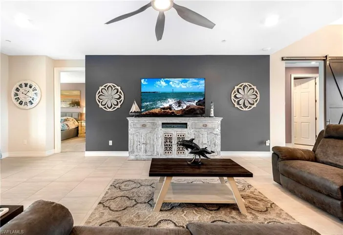 Tiled living room featuring ceiling fan and a barn door