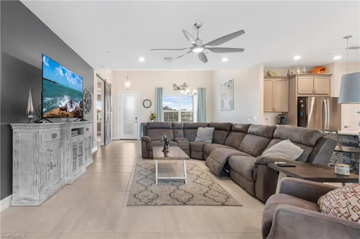 Living room featuring ceiling fan with notable chandelier and light tile patterned floors