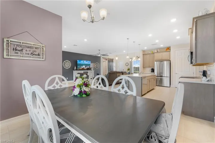 Dining room featuring ceiling fan with notable chandelier, sink, and light tile patterned flooring