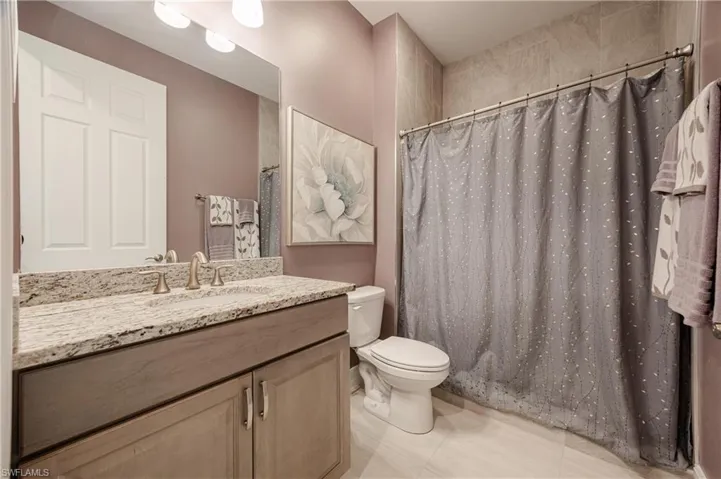 Bathroom with a shower with shower curtain, toilet, and vanity