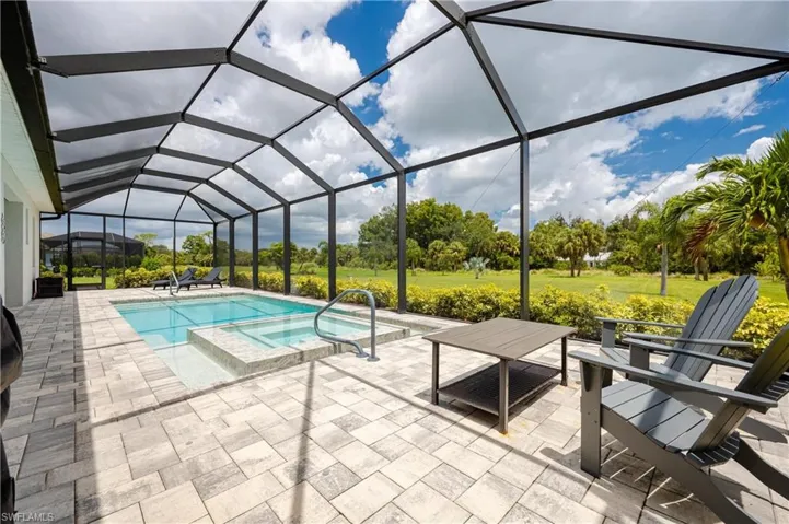 View of pool with a yard, glass enclosure, a patio area, and an in ground hot tub
