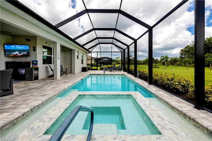 View of pool with a lanai, an in ground hot tub, a yard, and a patio