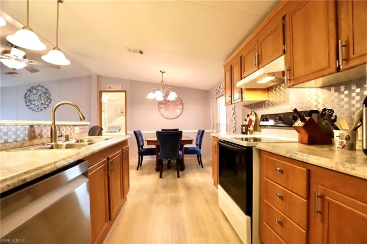 Kitchen featuring sink, electric range, light hardwood / wood-style floors, decorative light fixtures, and stainless steel dishwasher
