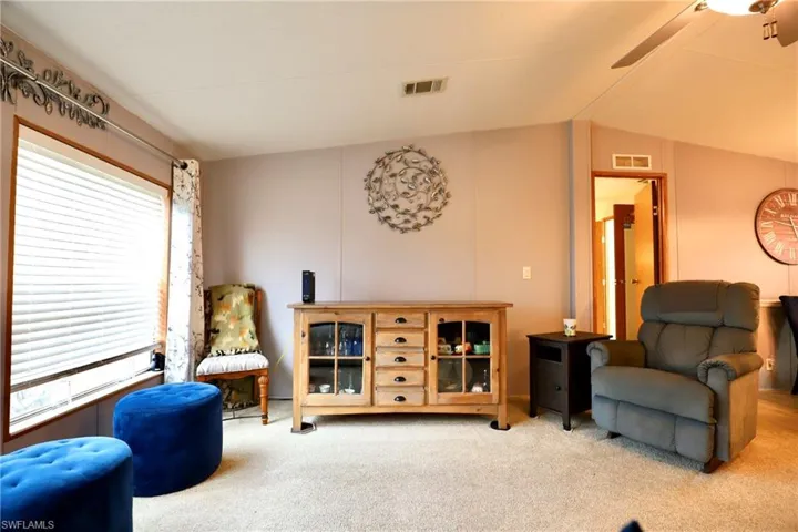 Living area featuring carpet, vaulted ceiling, and a healthy amount of sunlight