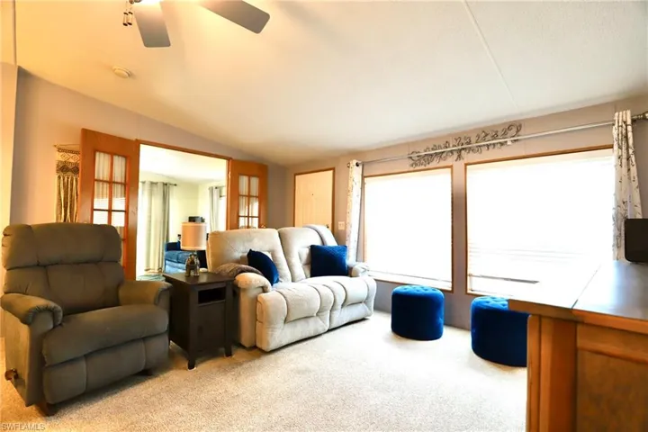 Carpeted living room featuring lofted ceiling and ceiling fan