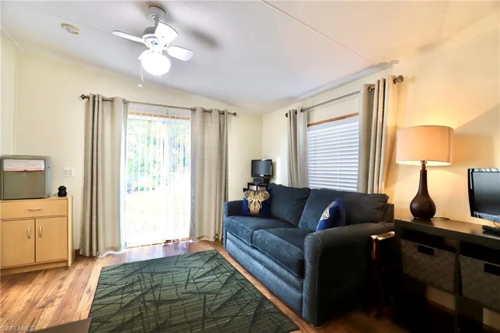 Living room featuring lofted ceiling, light wood-type flooring, and ceiling fan