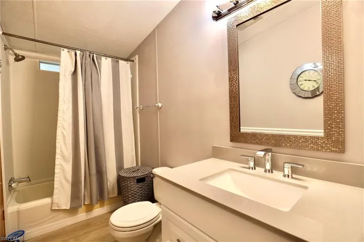 Full bathroom featuring hardwood / wood-style floors, a textured ceiling, toilet, shower / bath combo, and vanity