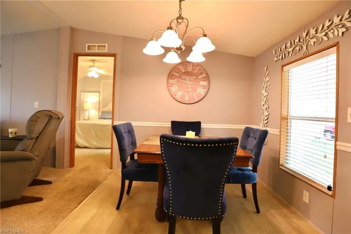 Dining room featuring hardwood / wood-style floors, ceiling fan with notable chandelier, and vaulted ceiling