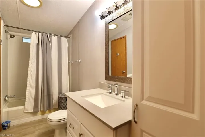 Full bathroom with wood-type flooring, a textured ceiling, shower / bath combo, toilet, and vanity
