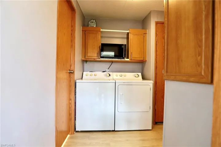 Laundry room with cabinets, light hardwood / wood-style flooring, and washing machine and dryer
