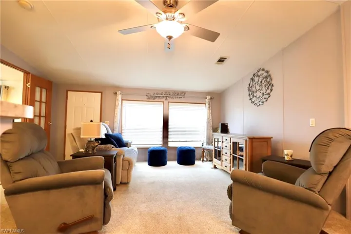 Living room with light carpet, lofted ceiling, and ceiling fan