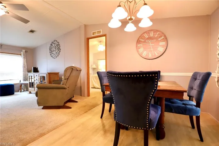Dining room with carpet floors, ceiling fan with notable chandelier, and vaulted ceiling