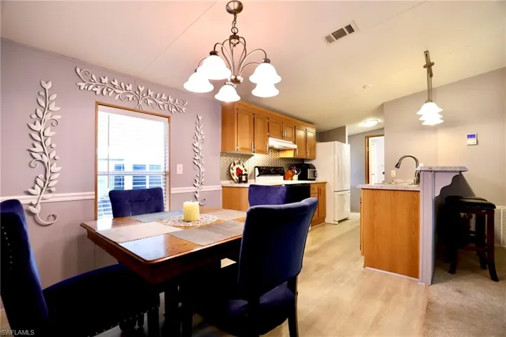Dining room with light hardwood / wood-style floors, a chandelier, and sink