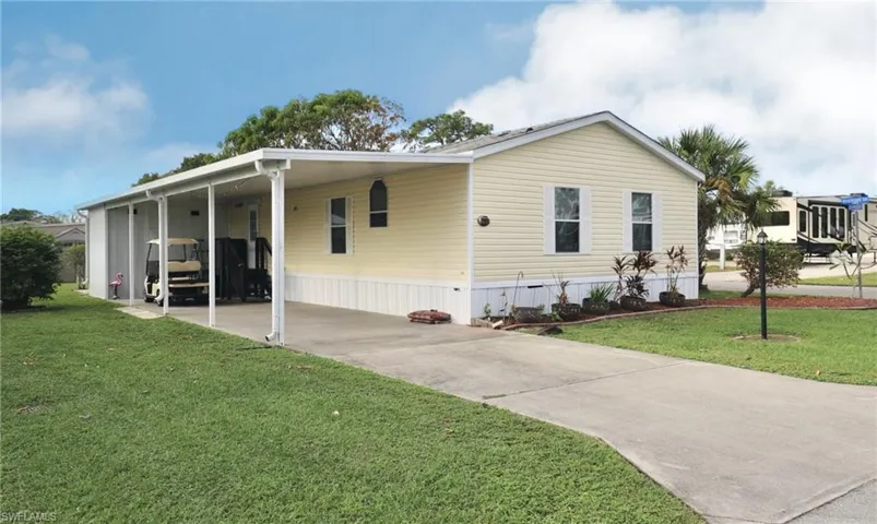 Manufactured / mobile home featuring a carport and a front yard
