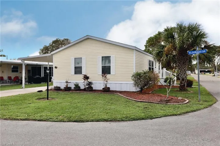 View of front facade featuring a front yard and a carport