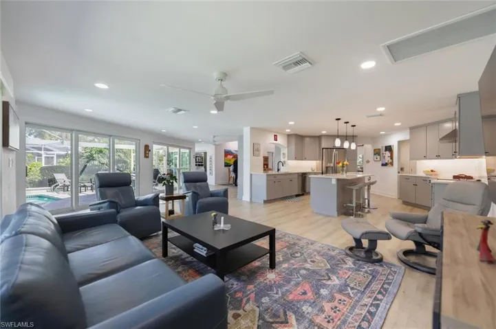 Living room featuring light wood-type flooring, a ceiling fan, and recessed lighting