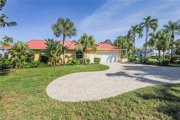 View of front facade with decorative driveway, a metal roof, a garage, and a front lawn