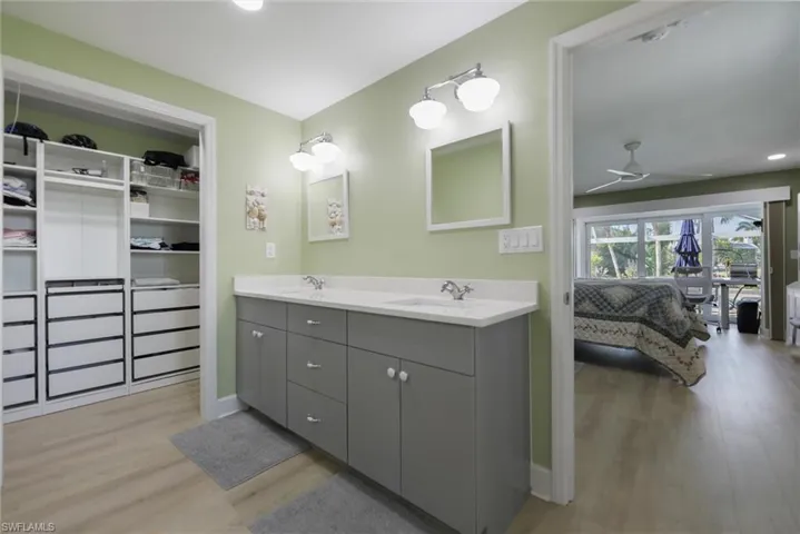 Full bathroom with ceiling fan, double vanity, light wood-style flooring, recessed lighting, and two walk in spacious closets