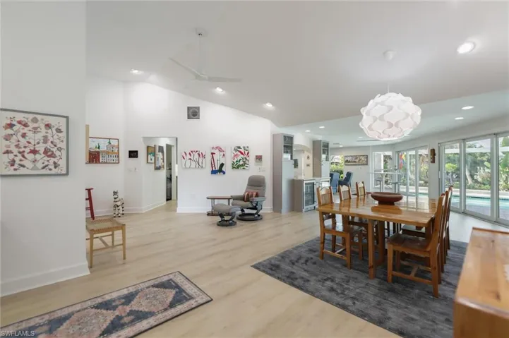 Dining area with lofted ceiling, light wood-type flooring, recessed lighting, wine cooler, and a ceiling fan