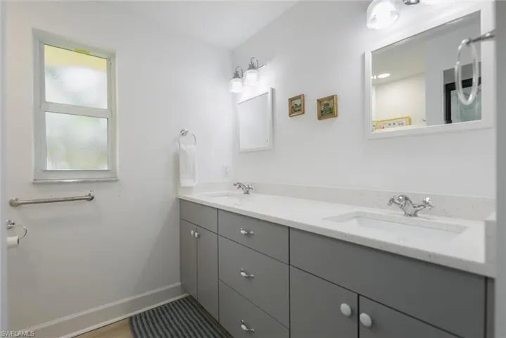 Full bathroom with double vanity and baseboards