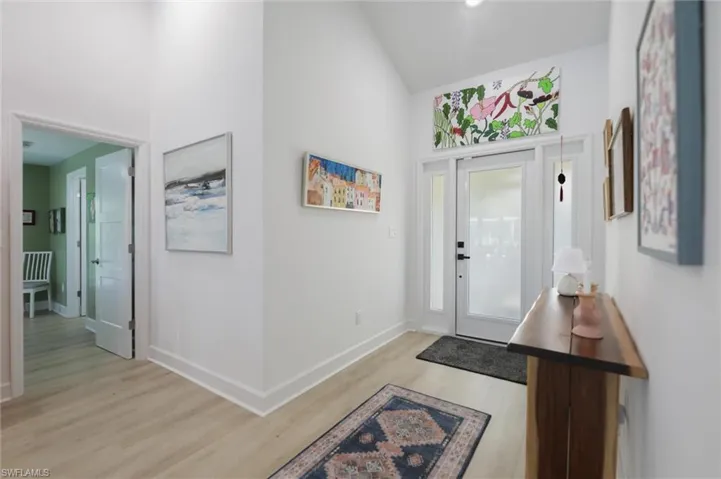 Foyer with light wood finished floors and high vaulted ceiling
