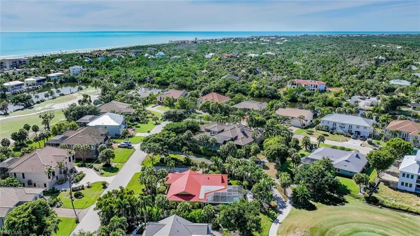 Aerial view of residential area featuring a nearby body of water and a golf course