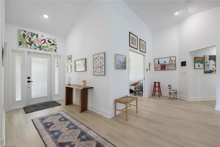 Foyer with high vaulted ceiling, light wood-style floors, and recessed lighting
