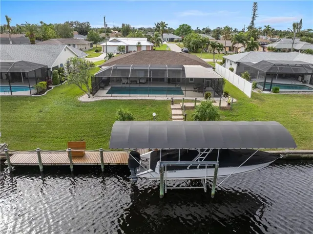 Low aerial view of boat lift, dock and backyard