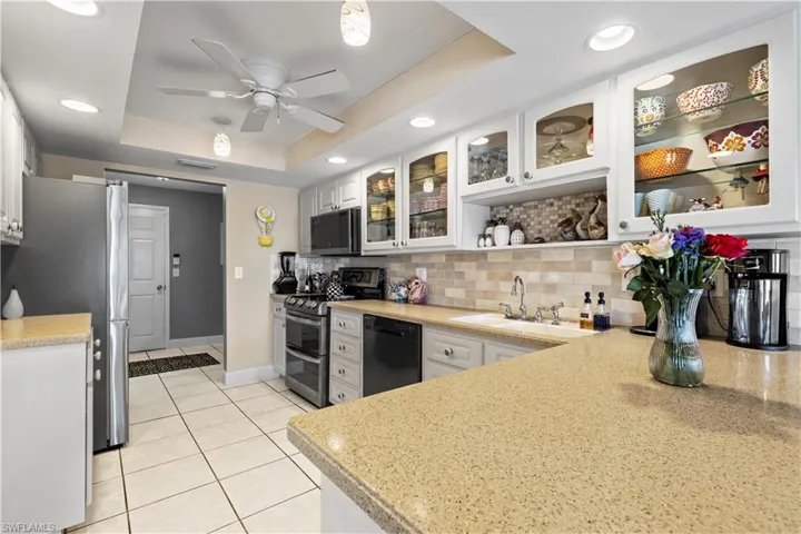 Kitchen featuring a raised ceiling, white cabinetry, sink, and appliances with stainless steel finishes