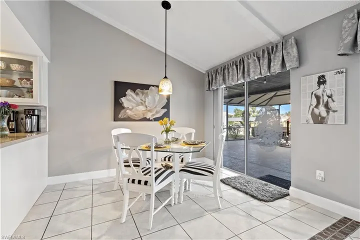 Tiled dining area featuring vaulted ceiling