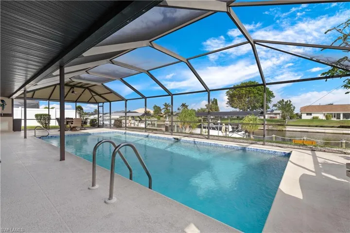 View of pool with a lanai, a patio area, and a water view