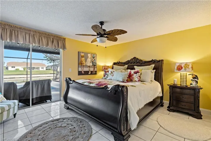 Third bedroom with light tile patterned floors, access to outside, and ceiling fan