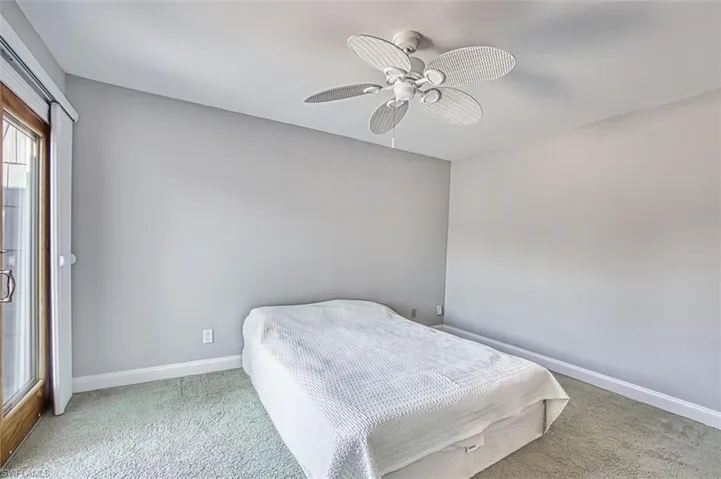 Carpeted bedroom featuring ceiling fan and baseboards