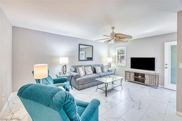 Living area featuring light marble finish floors and a ceiling fan