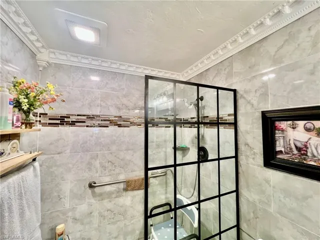 Primary bathroom with newly tiled walk in shower with crown molding.